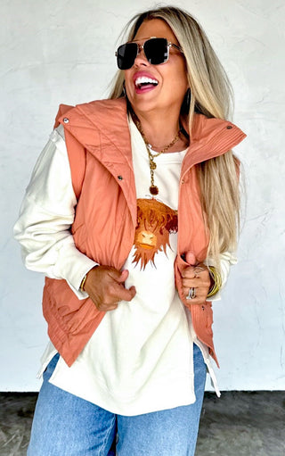 Boutique outfit featuring cream Highland Cow cozy sweatshirt layered under a rust vest, paired with relaxed denim.