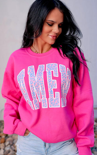 Woman wearing hot pink sweatshirt with AMEN screen print in big blue letters