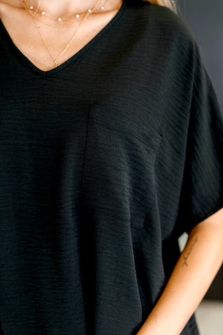 Close up of person wearing a black top showing textured fabric and pocket.