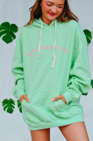Model wearing mint green hoodie with pink text and drawstring hood