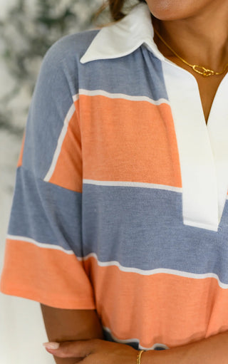 Close-up of a person wearing a striped shirt with orange, blue, and white colors.