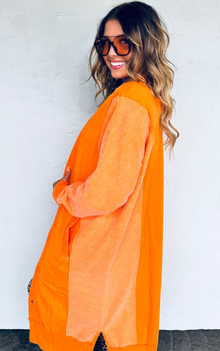 Woman wearing an orange cardigan against a white background
