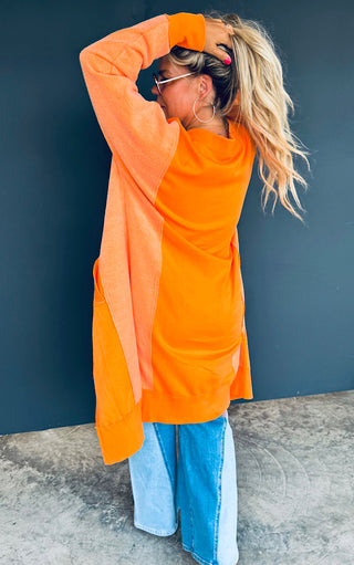 Woman wearing an orange cardigan with a blue background