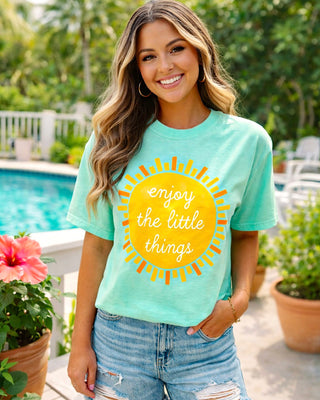 Mint green women’s graphic tee with sunshine design styled for summer with denim shorts by poolside.