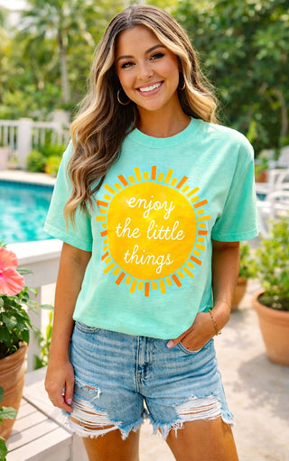 Southern boutique model wearing mint green sunshine graphic t-shirt with cut off denim shorts on patio.