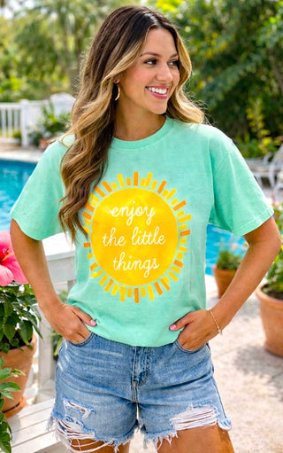 Mint Comfort Colors graphic tee with sunshine design and Enjoy the Little Things text on female model outdoors.