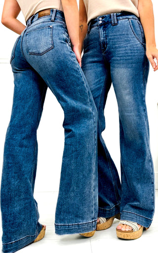 Two pairs of blue jeans being worn on a white background
