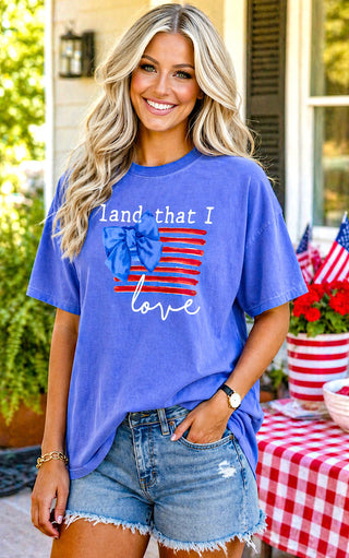 Woman wearing a blue t-shirt with an American flag design, standing outdoors.