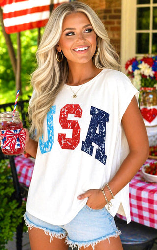 Woman wearing a 'USA' shirt outdoors with a table and American flag in the background