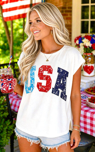Woman wearing a 'USA' t-shirt with a patriotic theme, holding a red drink at an outdoor event.