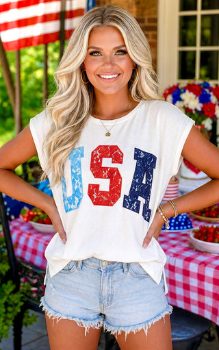 Woman wearing a 'USA' graphic t-shirt with American flag colors at a casual outdoor setting.