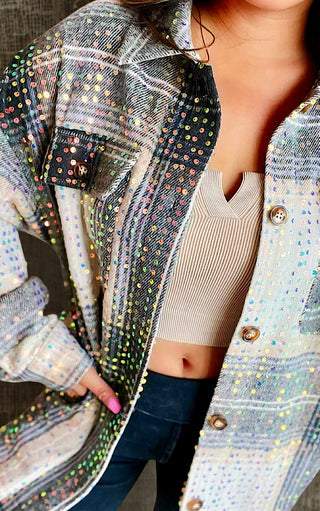 Close-up of a person wearing a multicolored sequined jacket with a neutral background.
