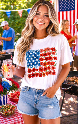 Woman wearing a white t-shirt with a colorful American flag design at a casual outdoor cookout.
