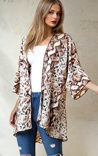 Model wearing a snakeskin print kimono cardigan over a white tank top with blue jeans.