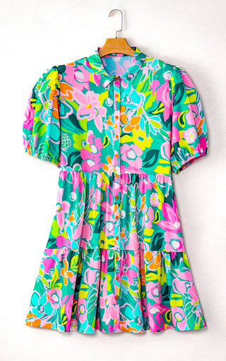 Colorful pink and green floral dress on a hanger with a white background