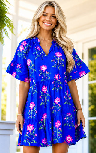 Woman wearing a blue floral dress standing outdoors.