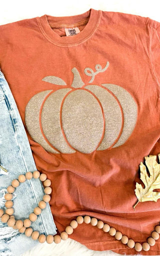 Coral t-shirt with a glittery pumpkin design, paired with denim jeans and wooden beads.