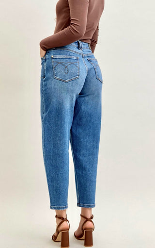 Person wearing blue jeans and a brown top on a plain background