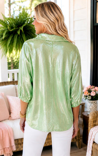 Back view of woman wearing a shimmer light green top and white pants.