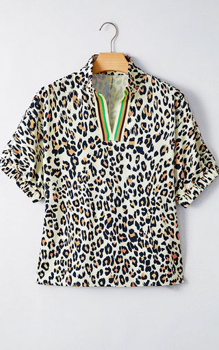 Leopard print blouse with striped trim split neckline displayed on a hanger against a plain light wall.