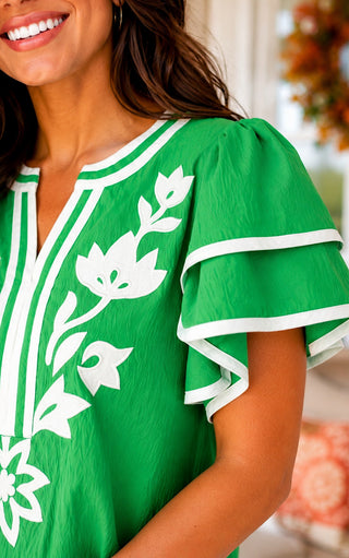 Close up of  Country Club Charm green embroidered ruffle sleeve top with white floral embroidery.