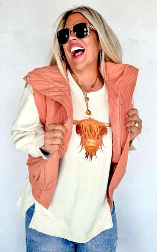 Model laughing while wearing Highland Cow cozy sweatshirt and rust vest combo, showcasing western-inspired embroidered cow design.