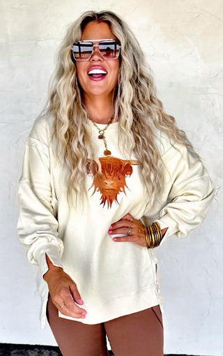 Close-up view of Highland Cow cozy sweatshirt styled with brown leggings, showing embroidered cow detail.