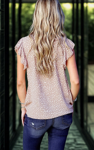 Back view of a blonde model in a taupe cheetah-print top with flutter sleeves, paired with distressed skinny jeans.