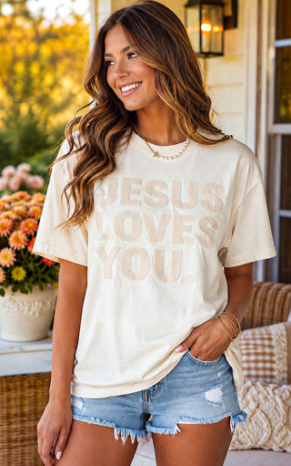 Woman wearing Comfort Colors Jesus Loves You faith-based graphic tee with tone-on-tone lettering and denim short