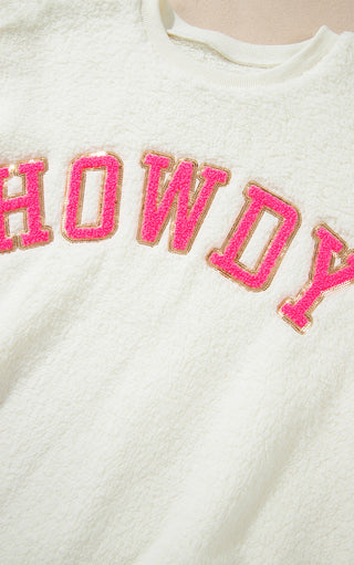 White sweater with pink 'HOWDY' text on a plain background