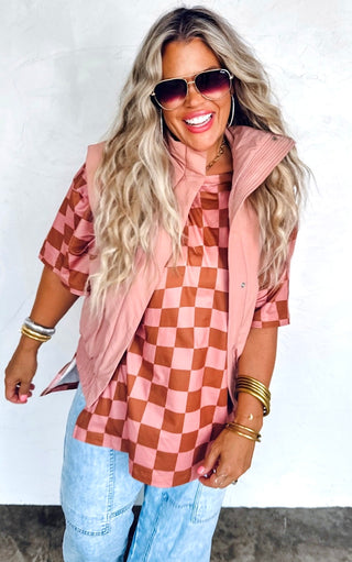 Woman wearing a pink and brown checkered shirt with a matching vest against a white background