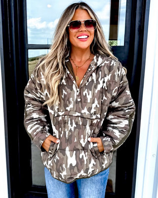 Woman wearing a camouflage puffer jacket and sunglasses outdoors