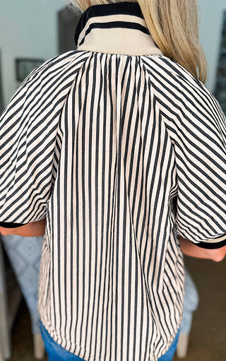 Back view of black and tan striped puff sleeve blouse with zip neckline women’s boutique fashion top styled with jeans 
