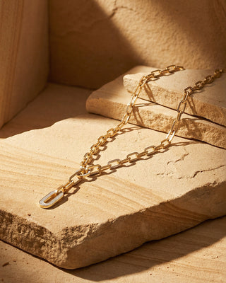 Gold chain necklace on a textured stone surface