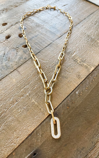 Gold chain necklace with a unique pendant on a wooden surface