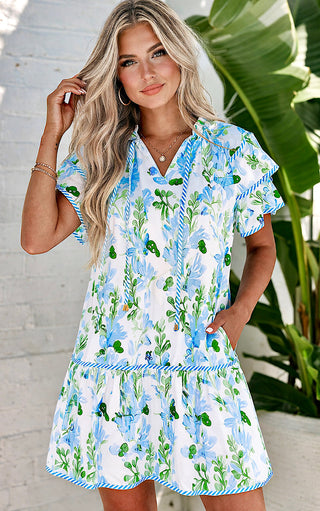 Woman wearing a blue floral dress with a plant in the background