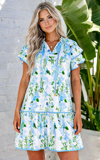 Model wearing Savannah Garden blue floral shift dress with flutter sleeves and ruffle hem.