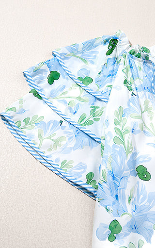 Up close view of sleeve of blue floral dress with contrast piping. 