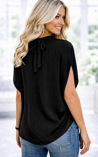 Back view of Woman wearing a black top with a bow detail in an indoor setting