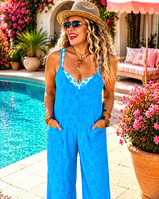 Blonde curly hair model wearing blue Terry cloth jumper swimsuit coverup.