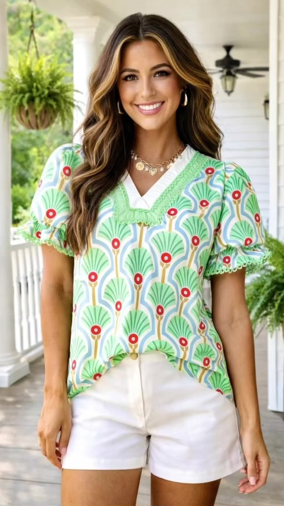 Video of model wearing green floral top with white shorts on a southern front porch