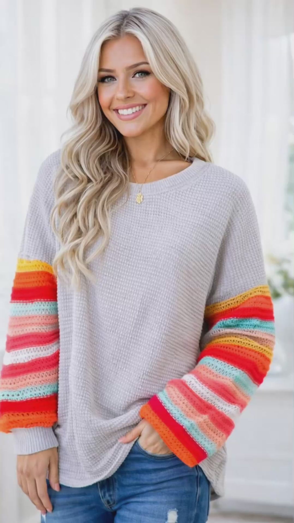 Video of Woman wearing a gray sweater with colorful sleeves indoors