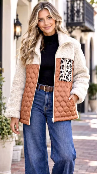 Video of a woman wearing a color block jacket with a cream sherpa fleece collar and sleeves, a quilted tan-brown body, and a leopard-print pocket panel, styled with a black turtleneck and blue jeans.