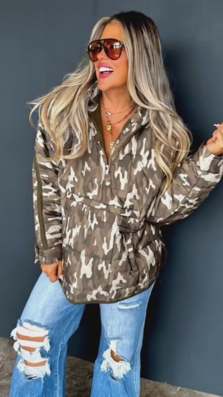 Video of woman modeling a camouflage puffy jacket with distressed flare jeans.