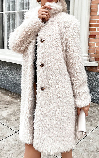 Female with ash blonde hair wearing long off white faux fur coat  