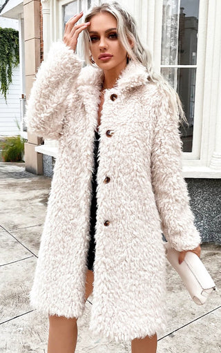 Female with ash blonde hair wearing long off white faux fur coat  